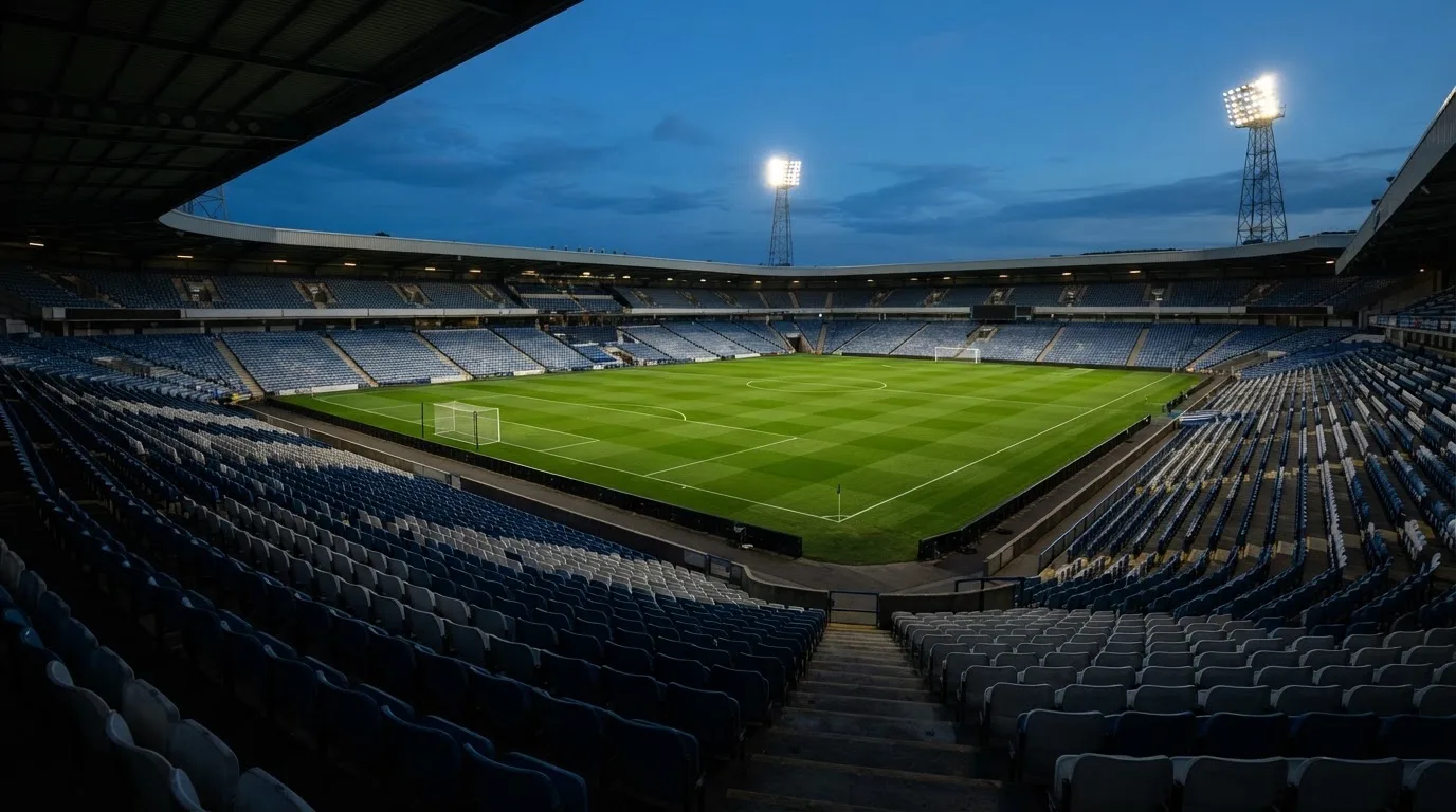 An empty football stadium with floodlight masts at dusk