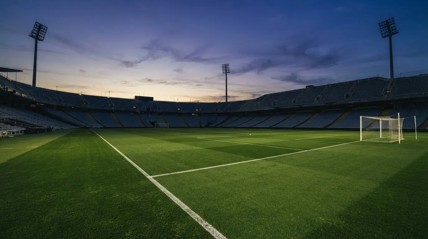 An empty football stadium with floodlight masts at dusk