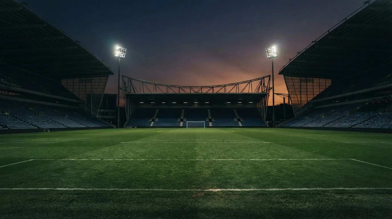 An empty football stadium with floodlight masts at dusk