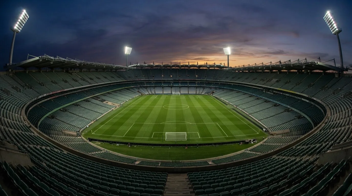 An empty football stadium with floodlight masts at dusk