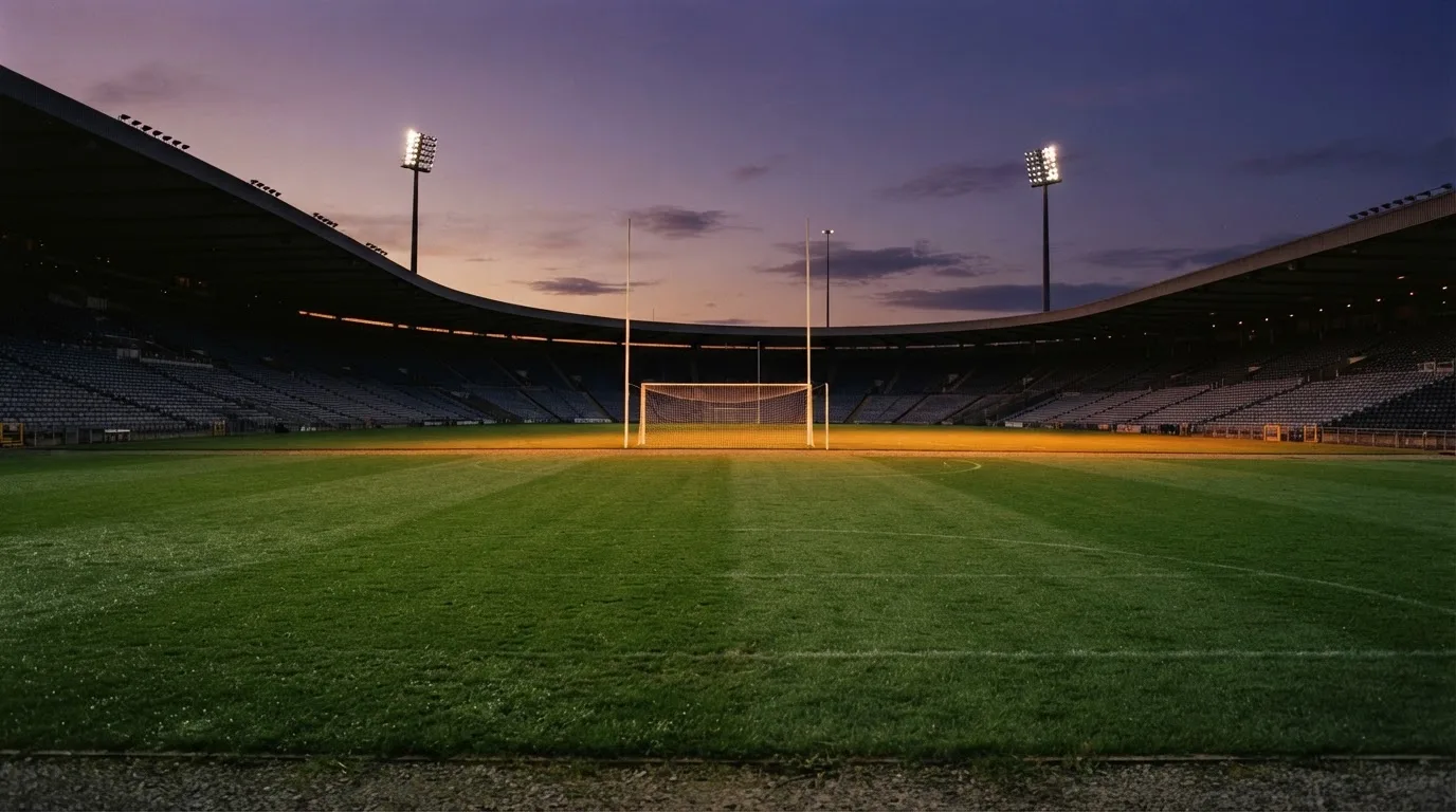 An empty football stadium with floodlight masts at dusk