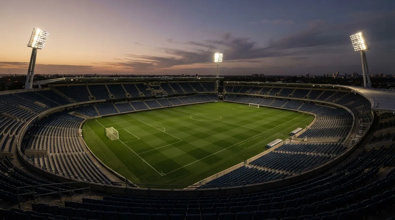 An empty football stadium with floodlight masts at dusk