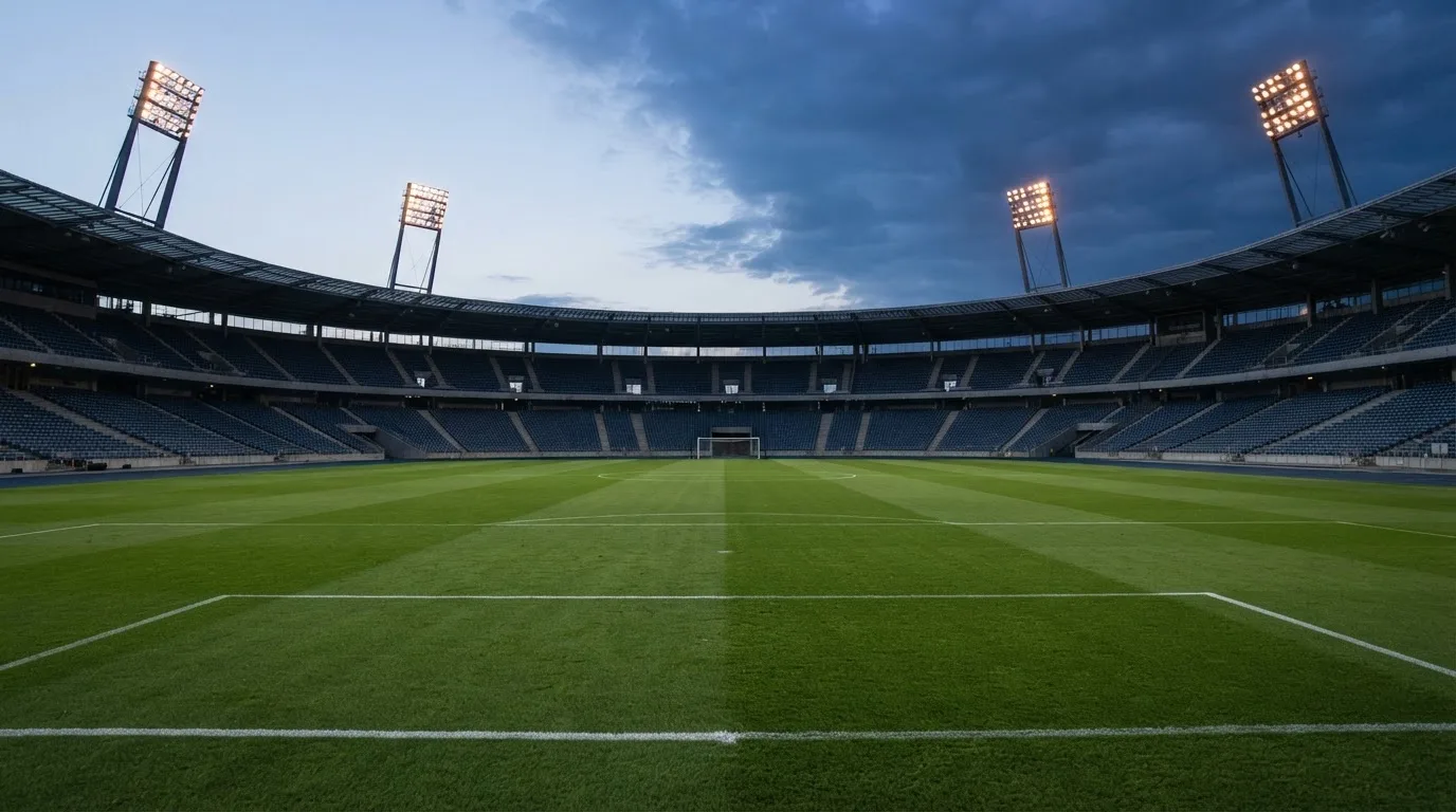 An empty football stadium with floodlight masts at dusk