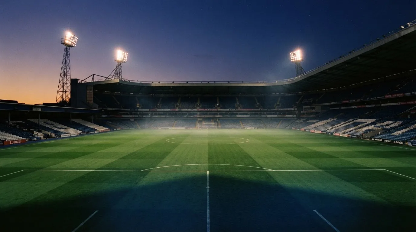 An empty football stadium with floodlight masts at dusk