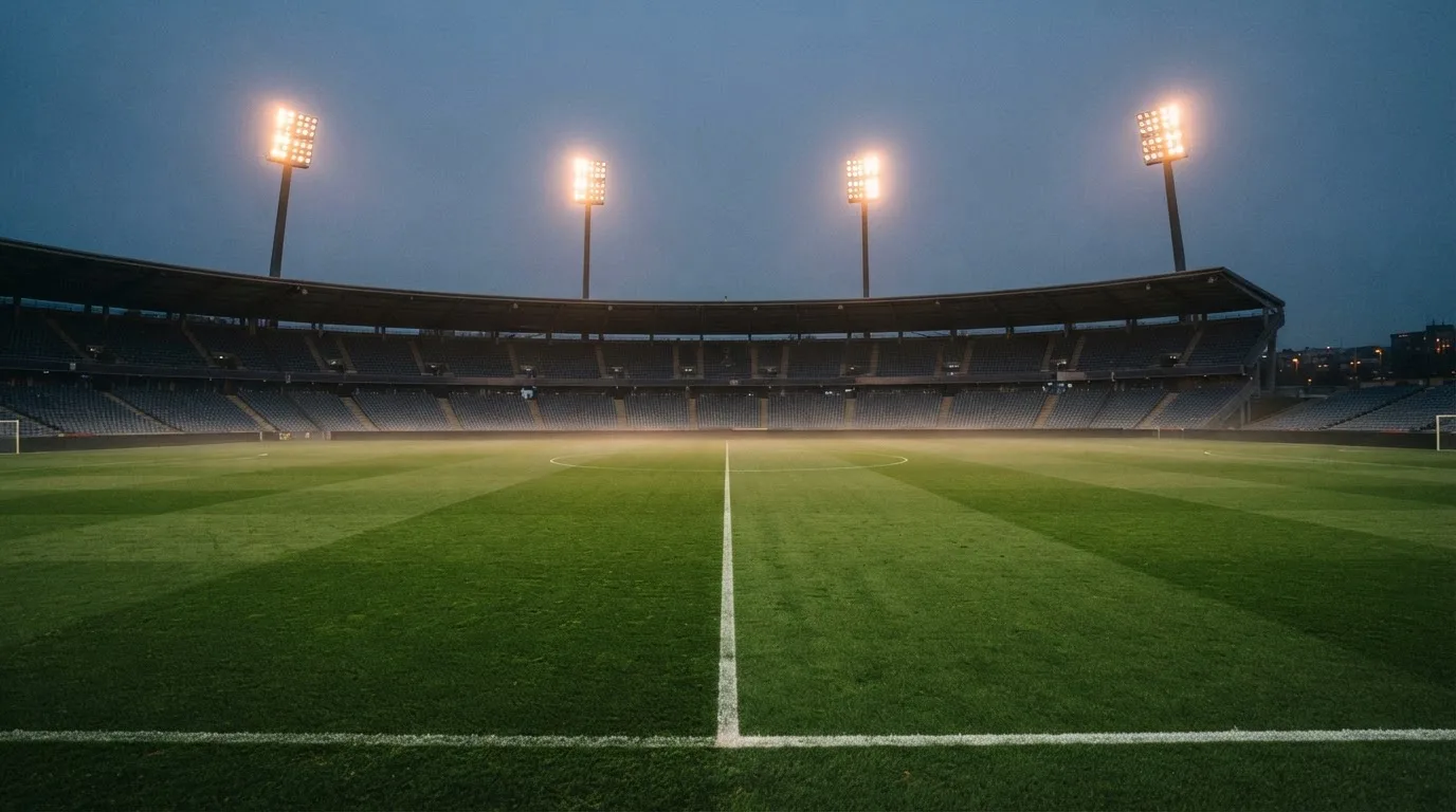 An empty football stadium with floodlight masts at dusk
