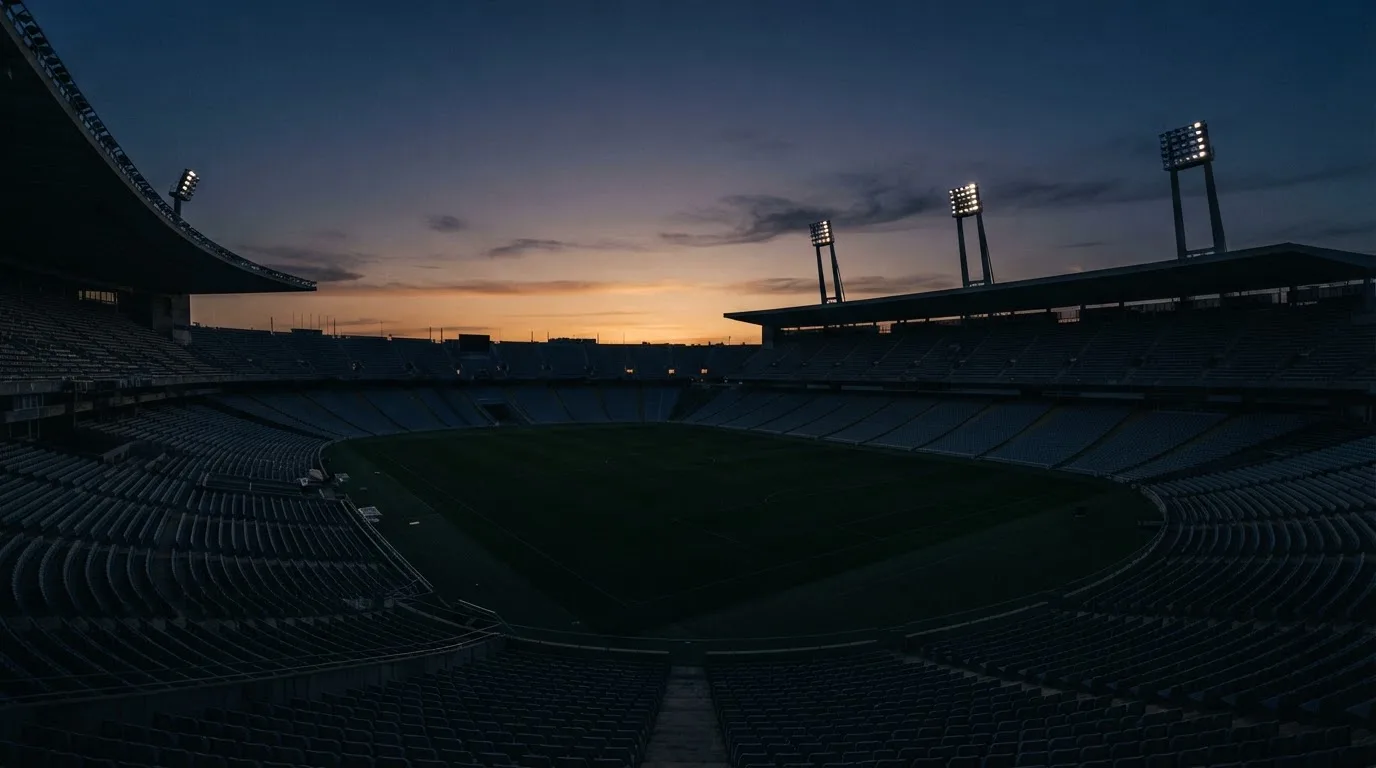 An empty football stadium with floodlight masts at dusk