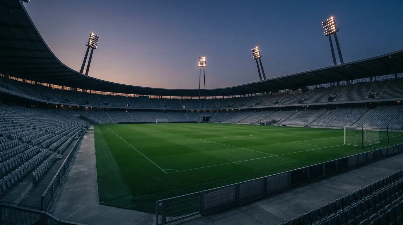 An empty football stadium with floodlight masts at dusk