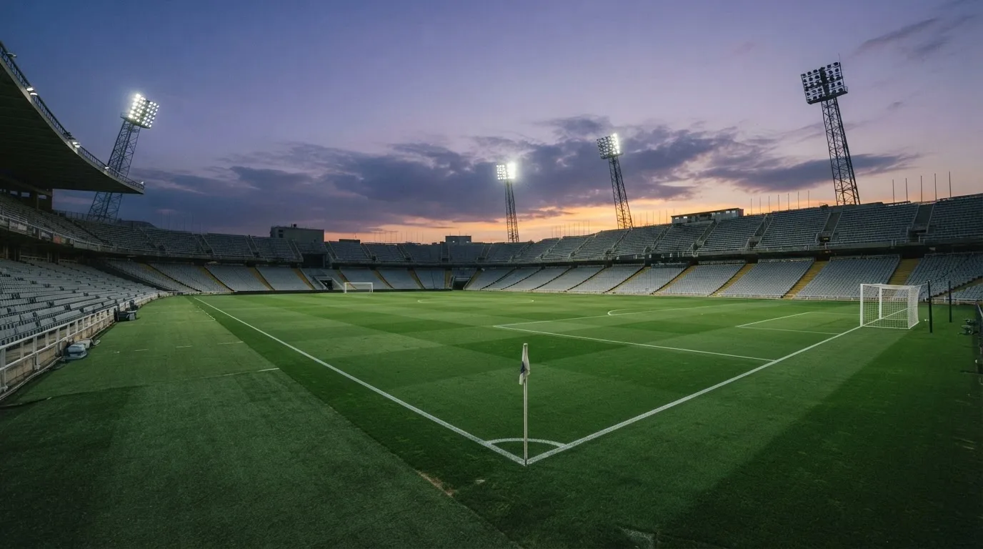 An empty football stadium with floodlight masts at dusk