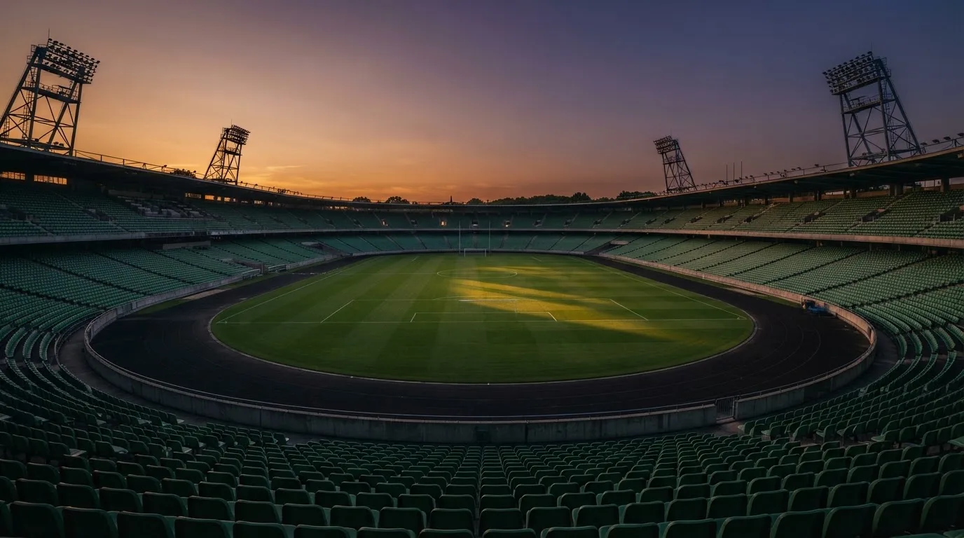 An empty football stadium with floodlight masts at dusk