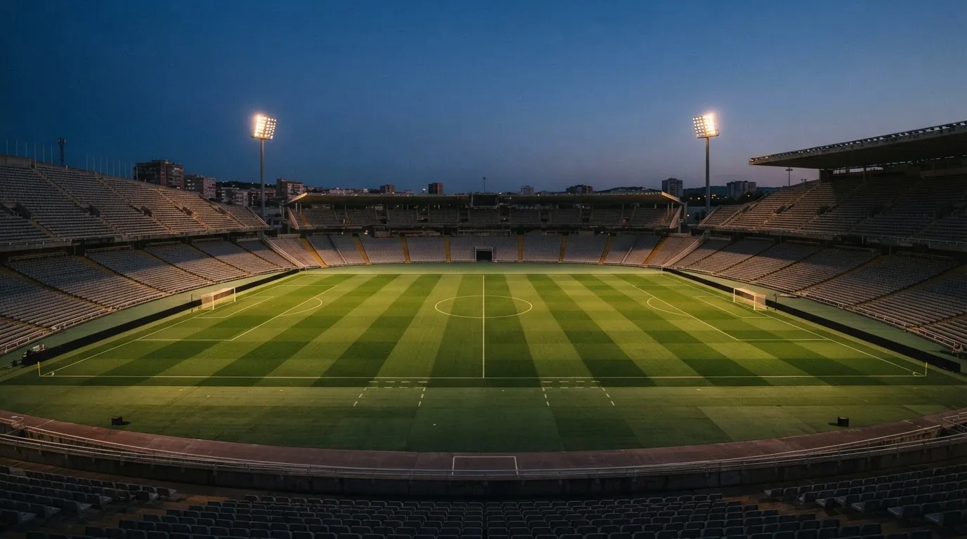 An empty football stadium with floodlight masts at dusk