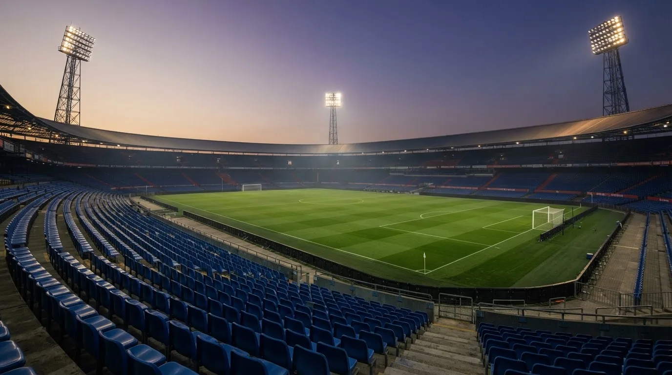 An empty football stadium with floodlight masts at dusk