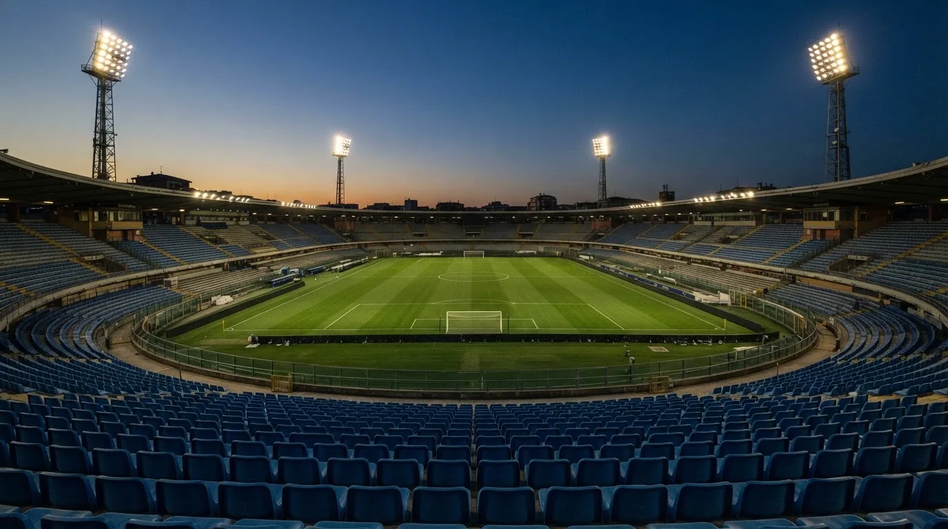 An empty football stadium with floodlight masts at dusk