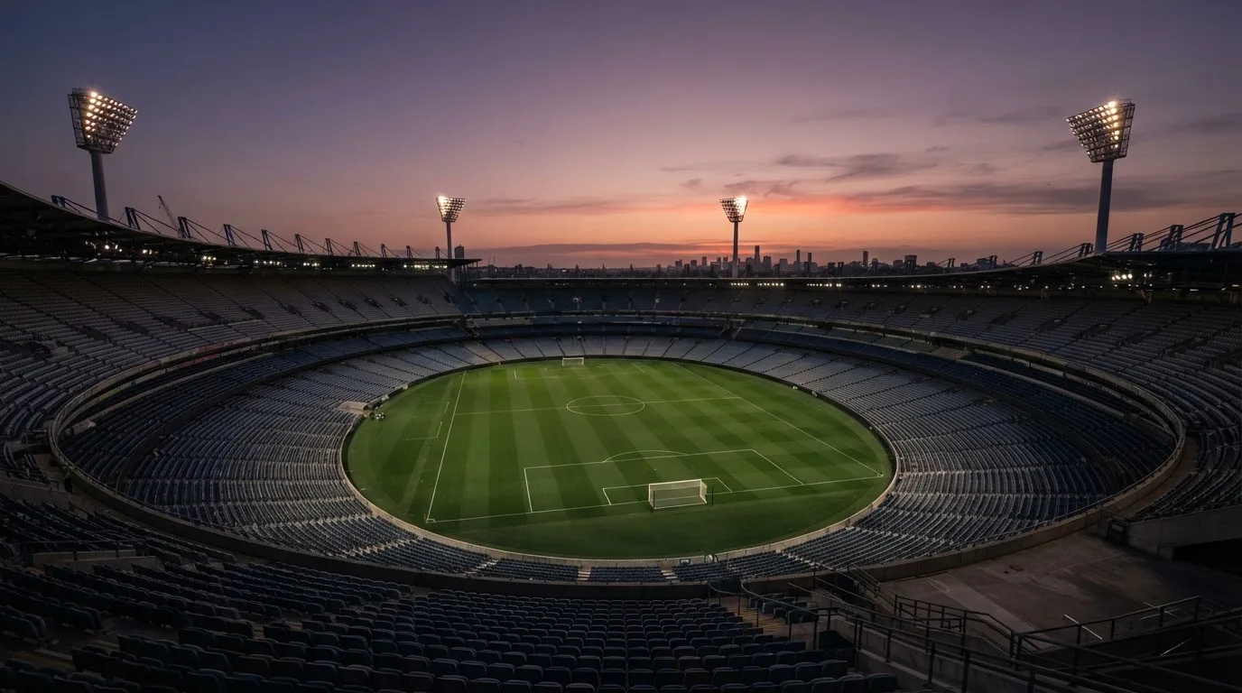 An empty football stadium with floodlight masts at dusk