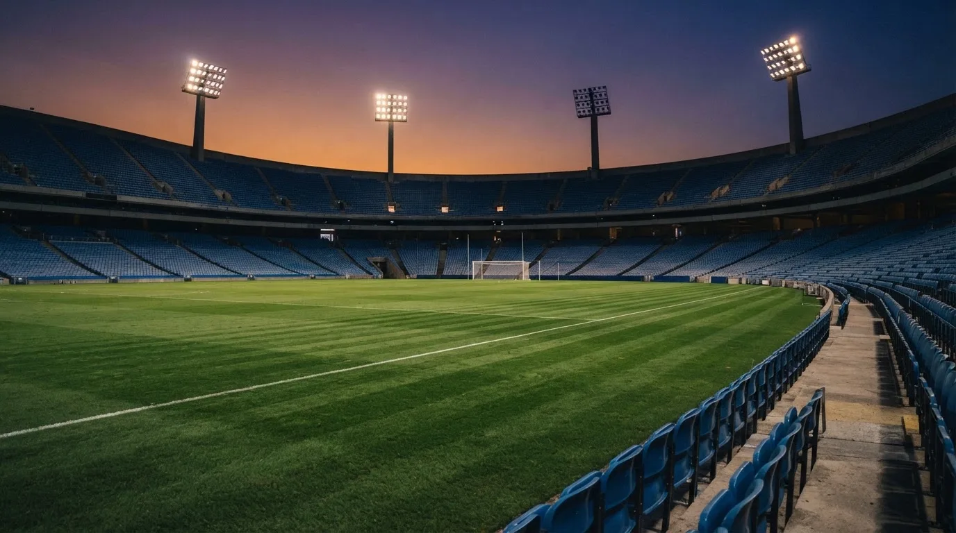 An empty football stadium with floodlight masts at dusk