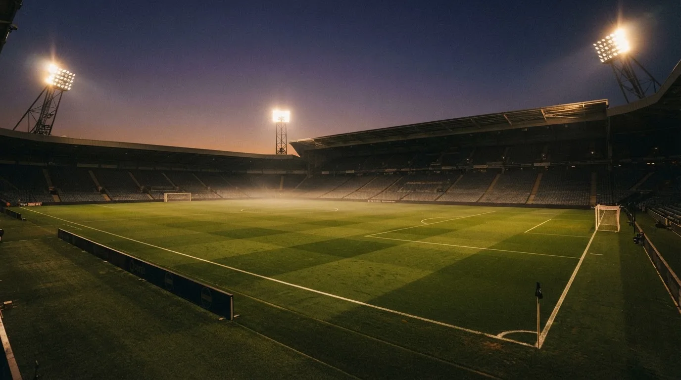 An empty football stadium with floodlight masts at dusk
