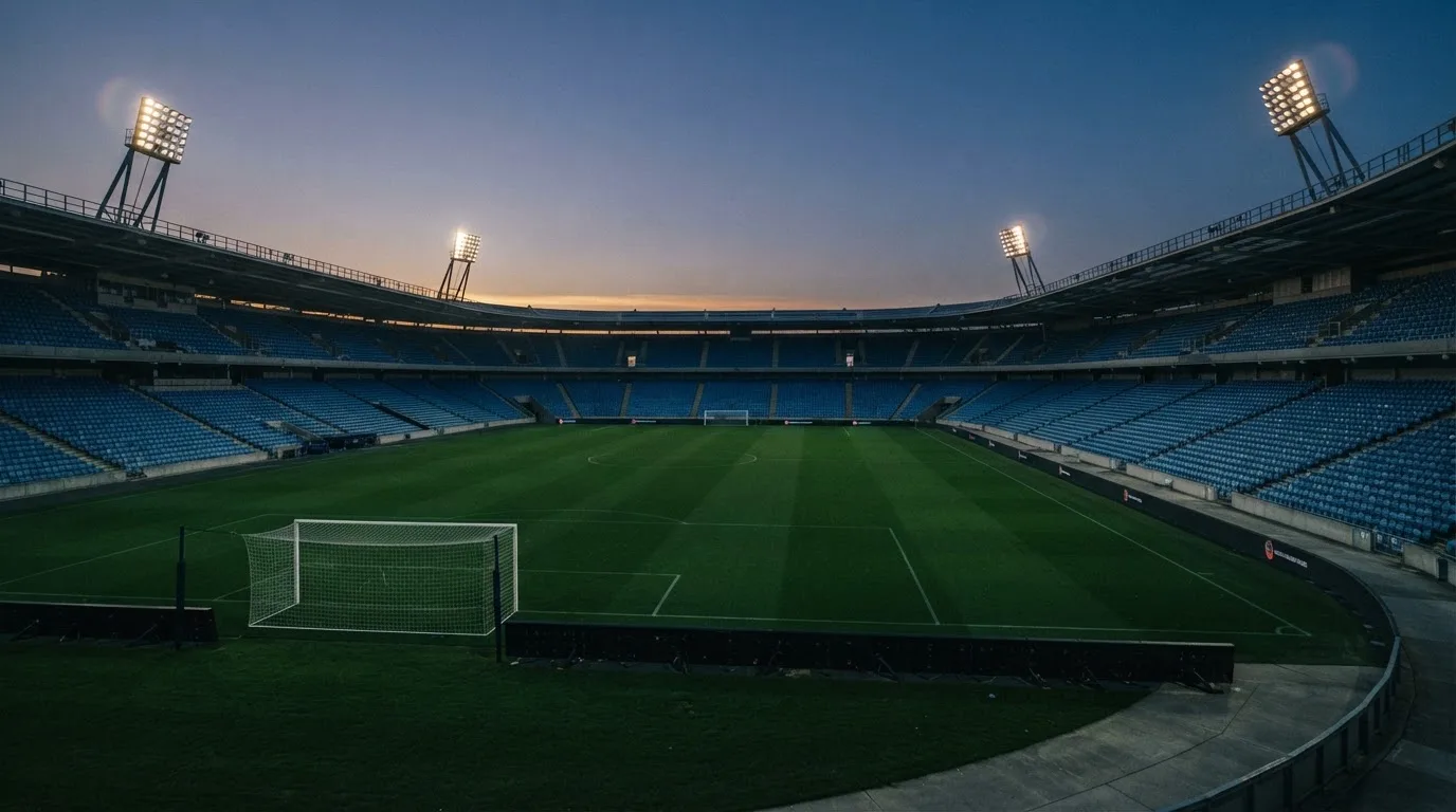 An empty football stadium with floodlight masts at dusk