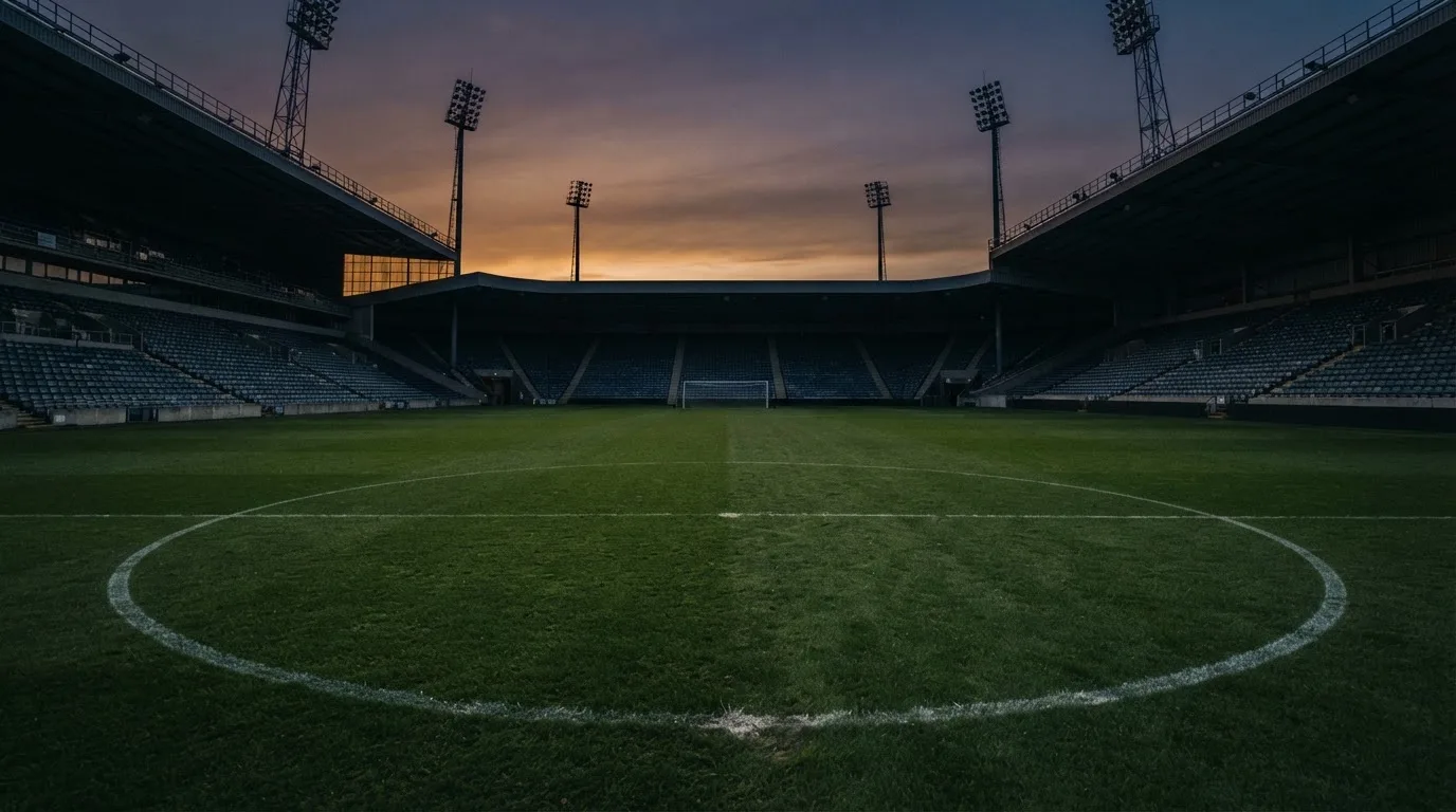 An empty football stadium with floodlight masts at dusk