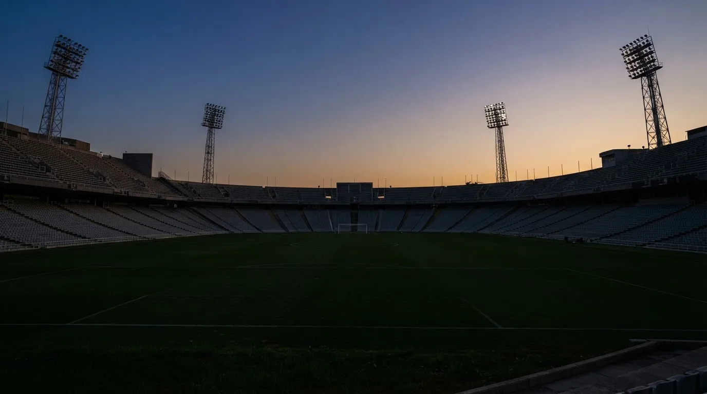 An empty football stadium with floodlight masts at dusk