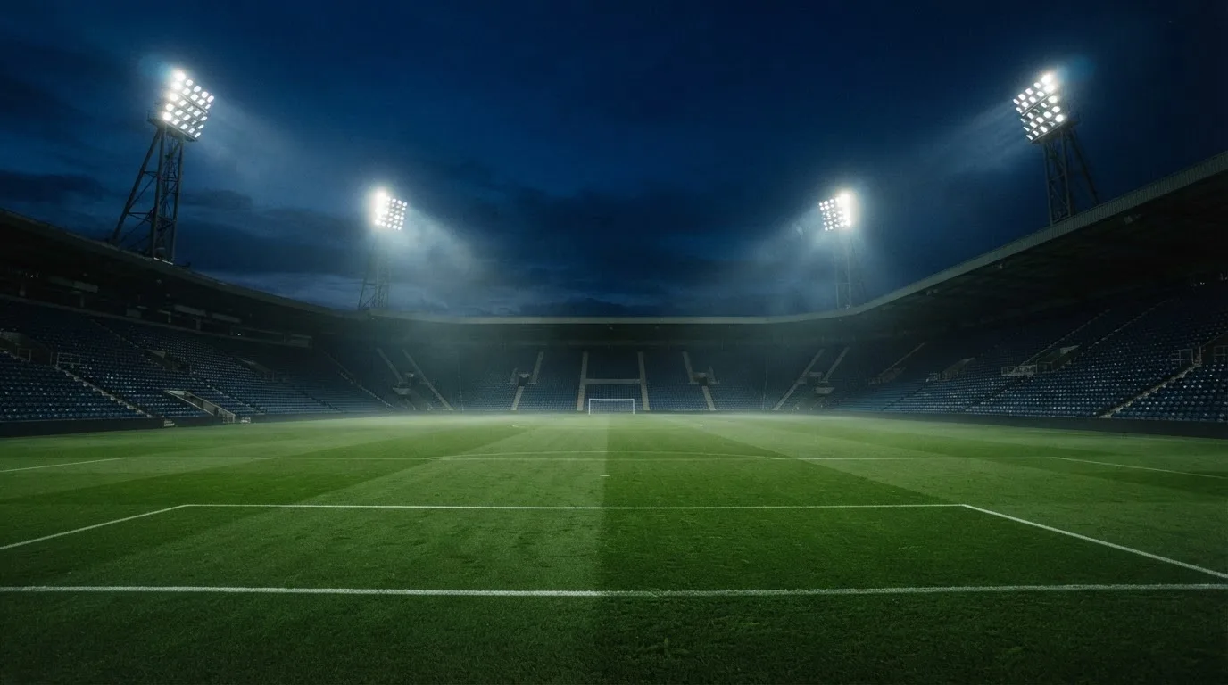 An empty football stadium with floodlight masts at dusk
