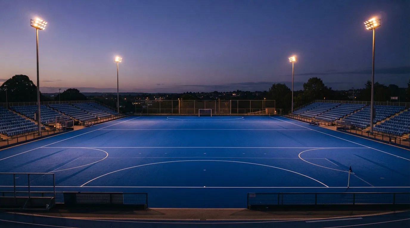 An empty football stadium with floodlight masts at dusk