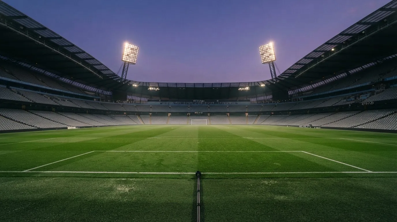 An empty football stadium with floodlight masts at dusk