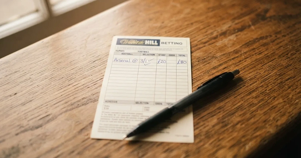 A blank paper betting slip beside a pen on a wooden counter