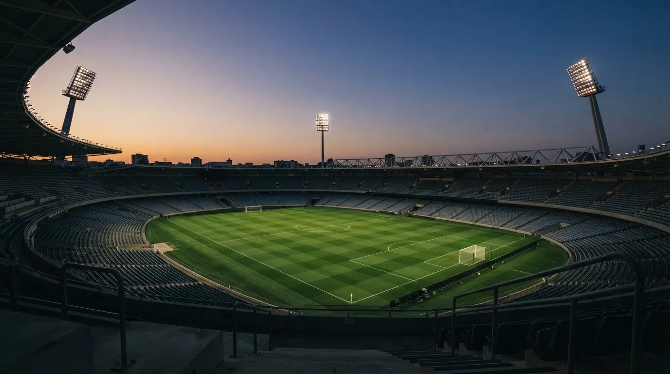 An empty football stadium with floodlight masts at dusk