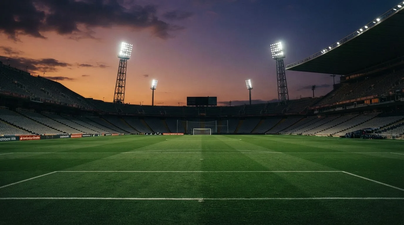 An empty football stadium with floodlight masts at dusk