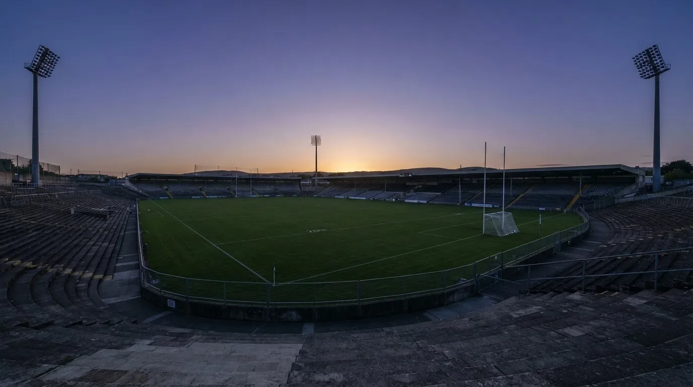 An empty football stadium with floodlight masts at dusk