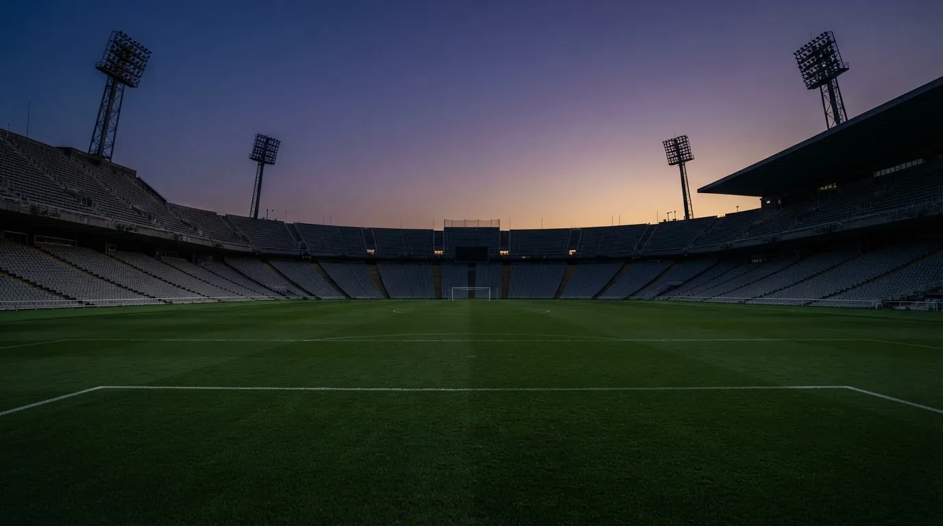 An empty football stadium with floodlight masts at dusk