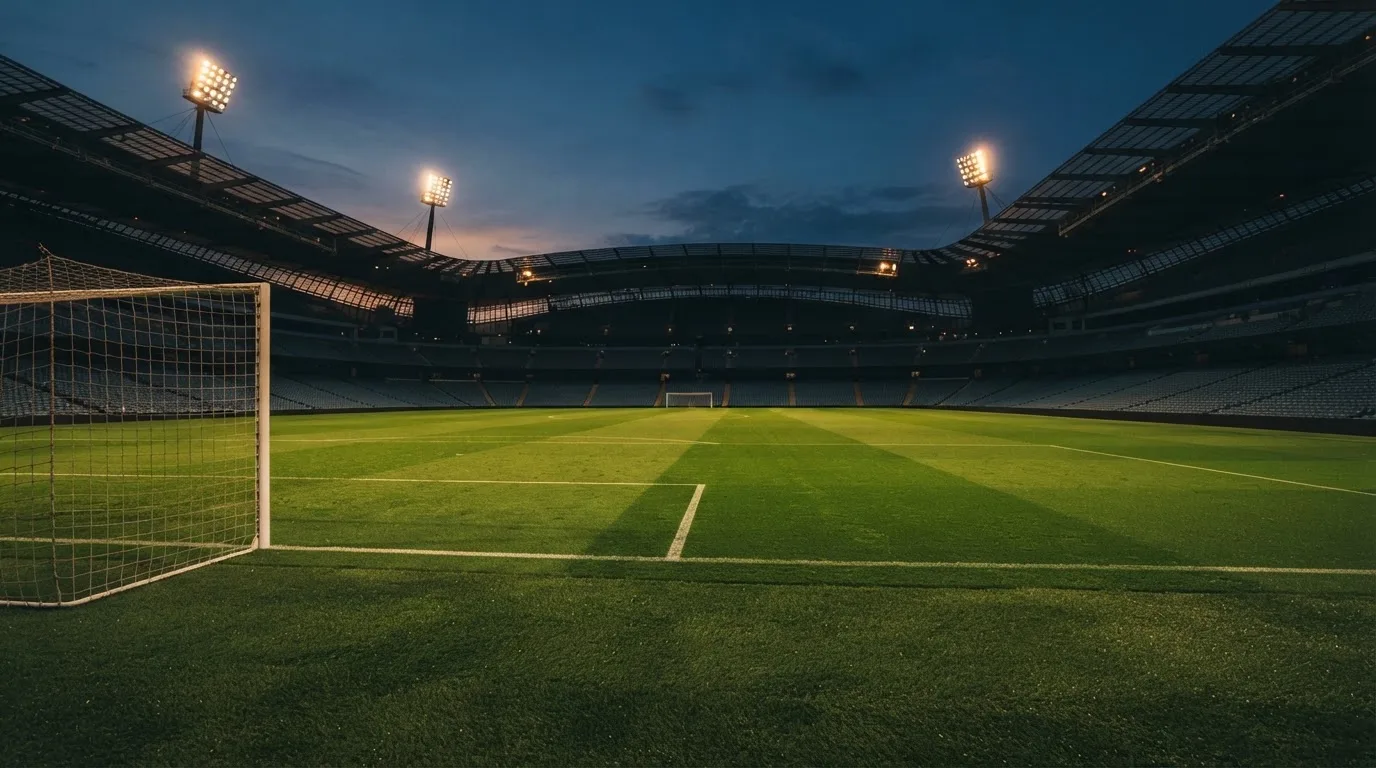 An empty football stadium with floodlight masts at dusk
