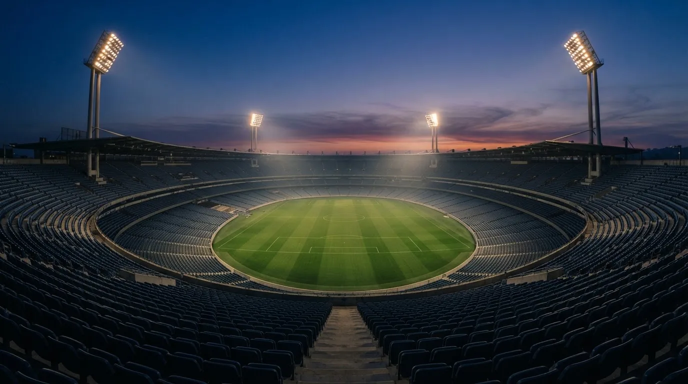 An empty football stadium with floodlight masts at dusk