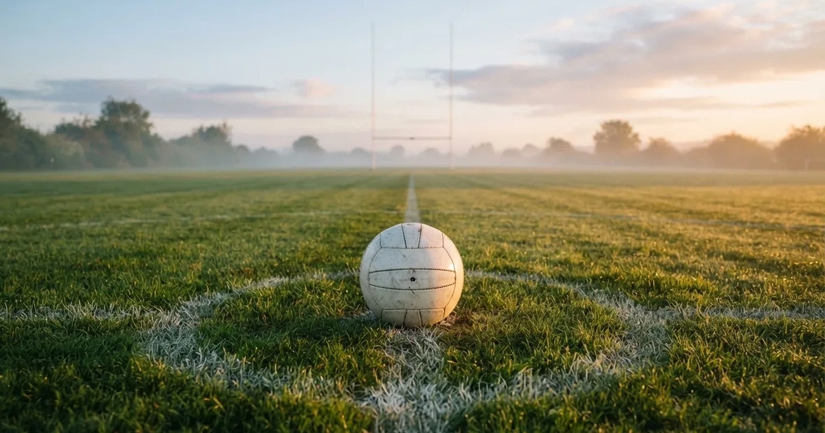A ball on the centre spot of a grass pitch in morning light