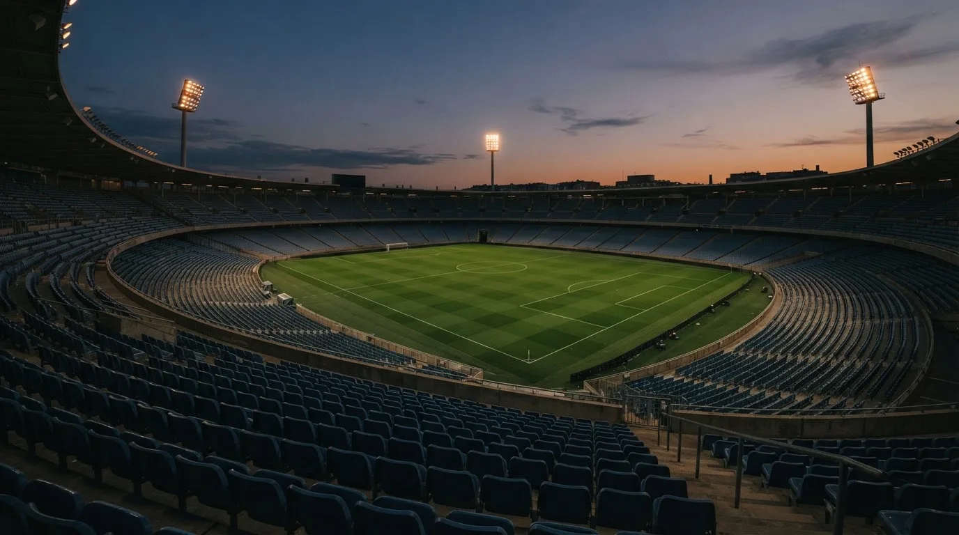 An empty football stadium with floodlight masts at dusk
