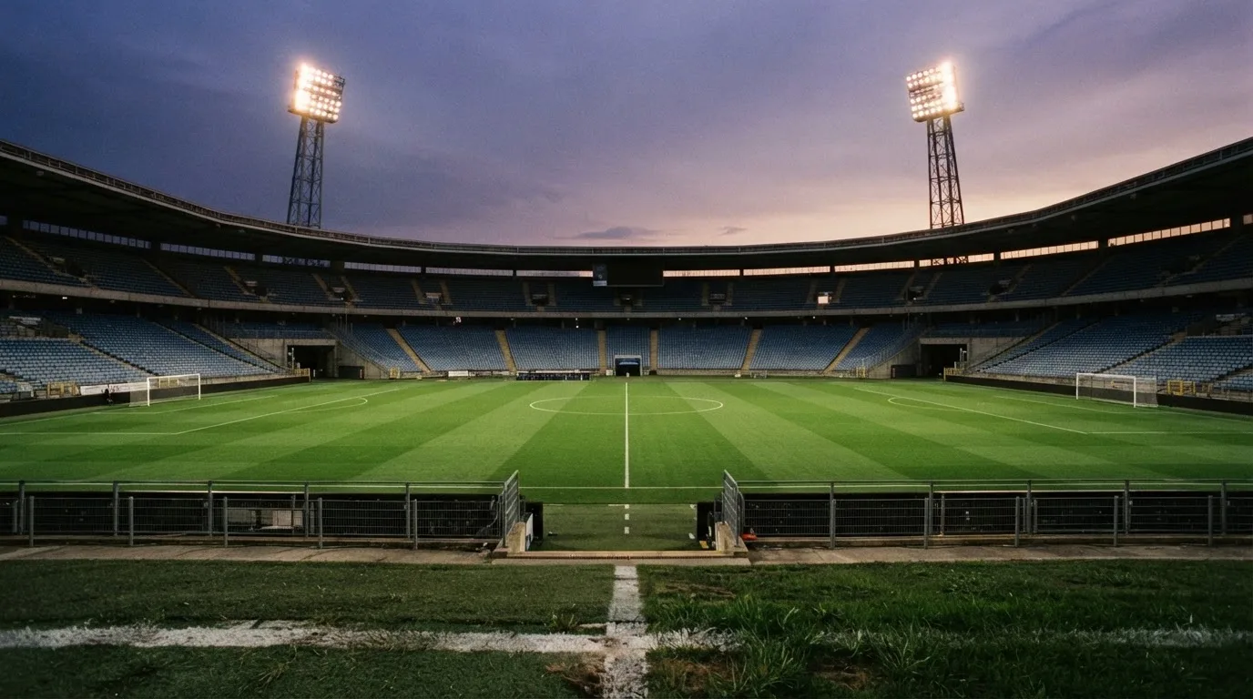 An empty football stadium with floodlight masts at dusk