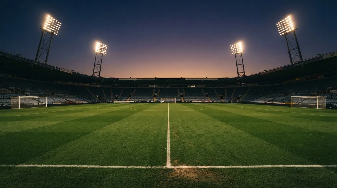 An empty football stadium with floodlight masts at dusk