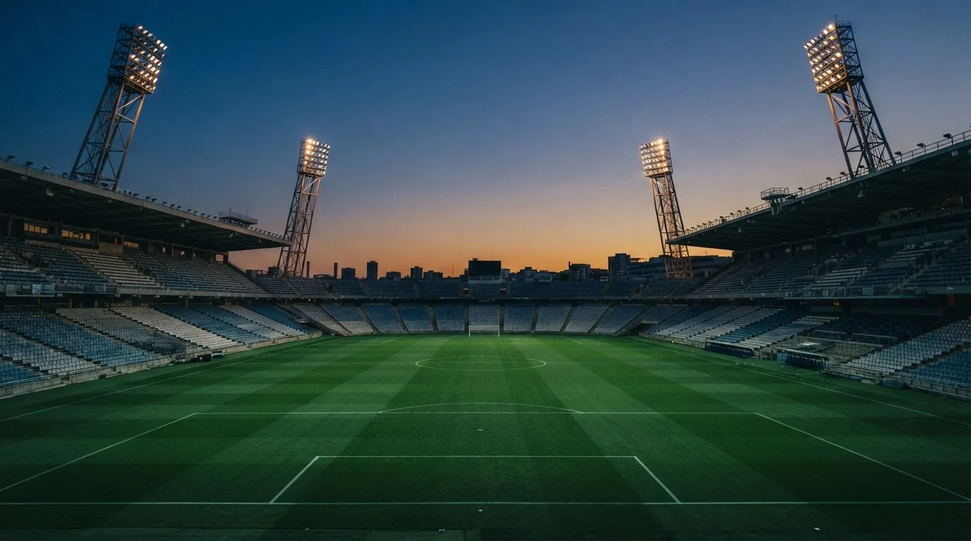 An empty football stadium with floodlight masts at dusk