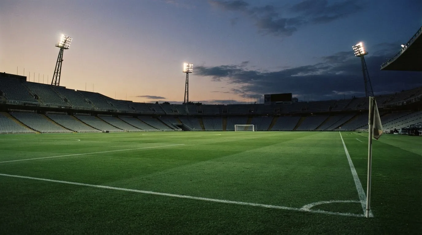 An empty football stadium with floodlight masts at dusk