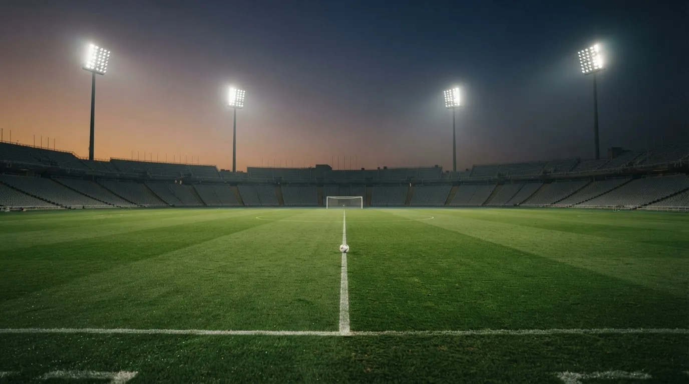 An empty football stadium with floodlight masts at dusk