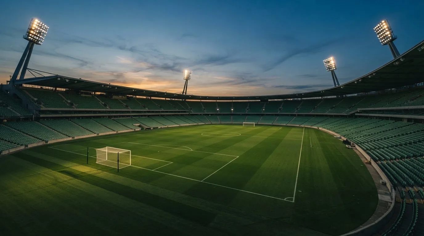 An empty football stadium with floodlight masts at dusk