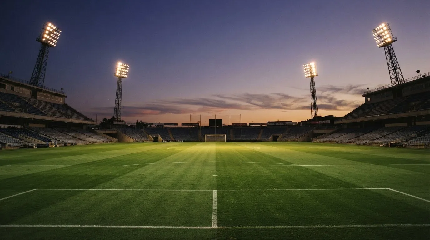 An empty football stadium with floodlight masts at dusk
