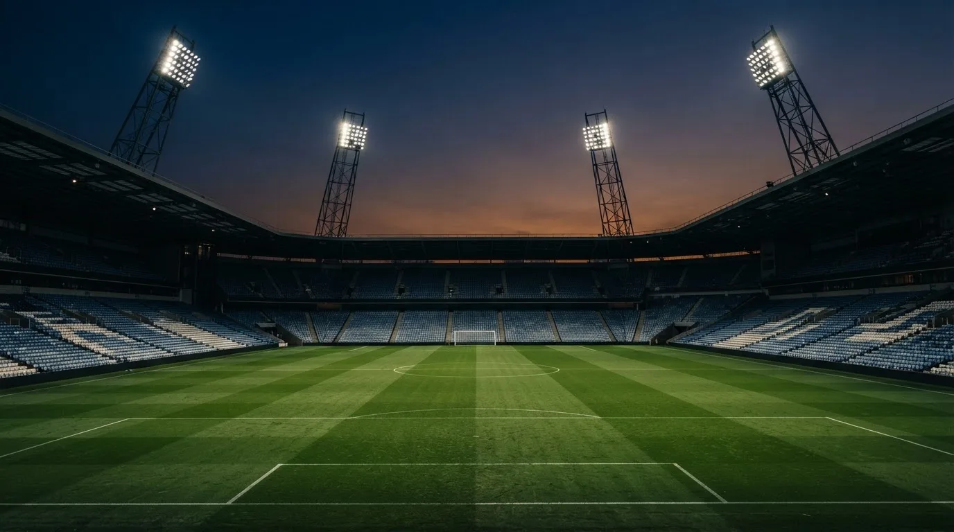 An empty football stadium with floodlight masts at dusk