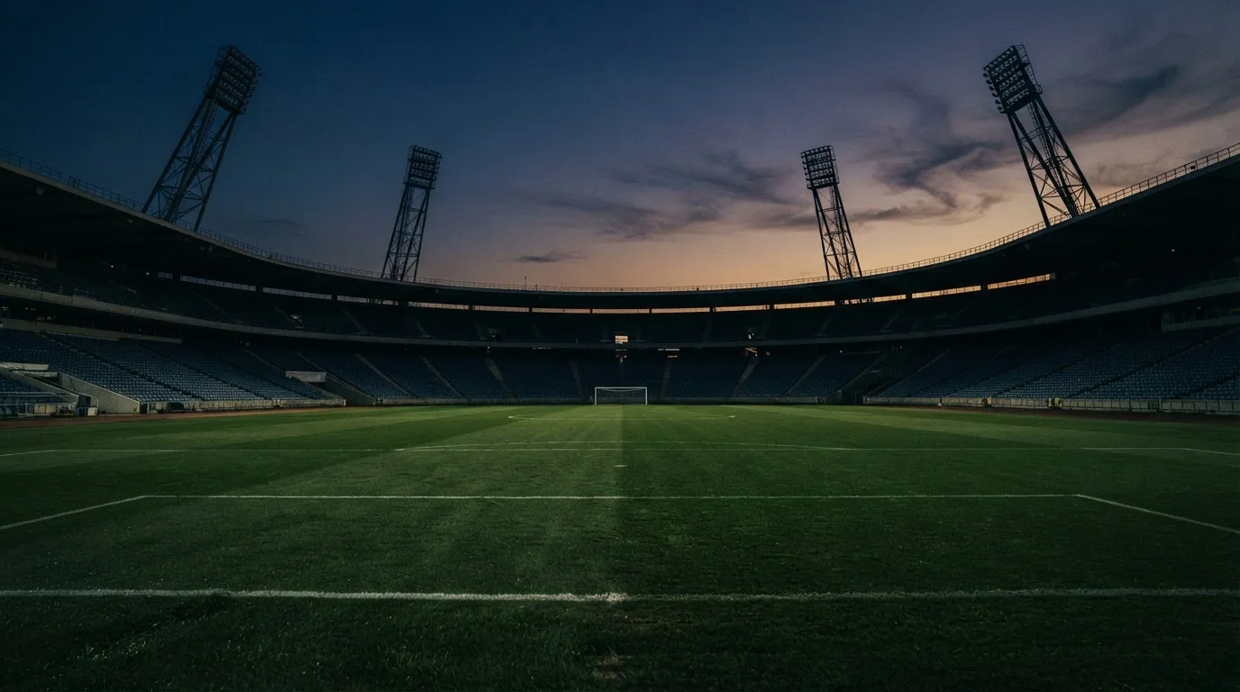 An empty football stadium with floodlight masts at dusk