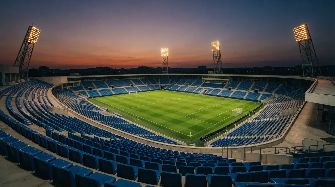 An empty football stadium with floodlight masts at dusk