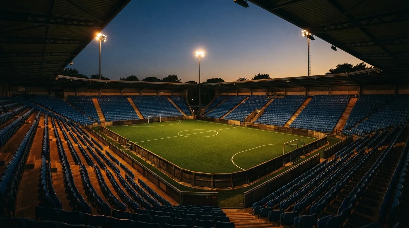 An empty football stadium with floodlight masts at dusk