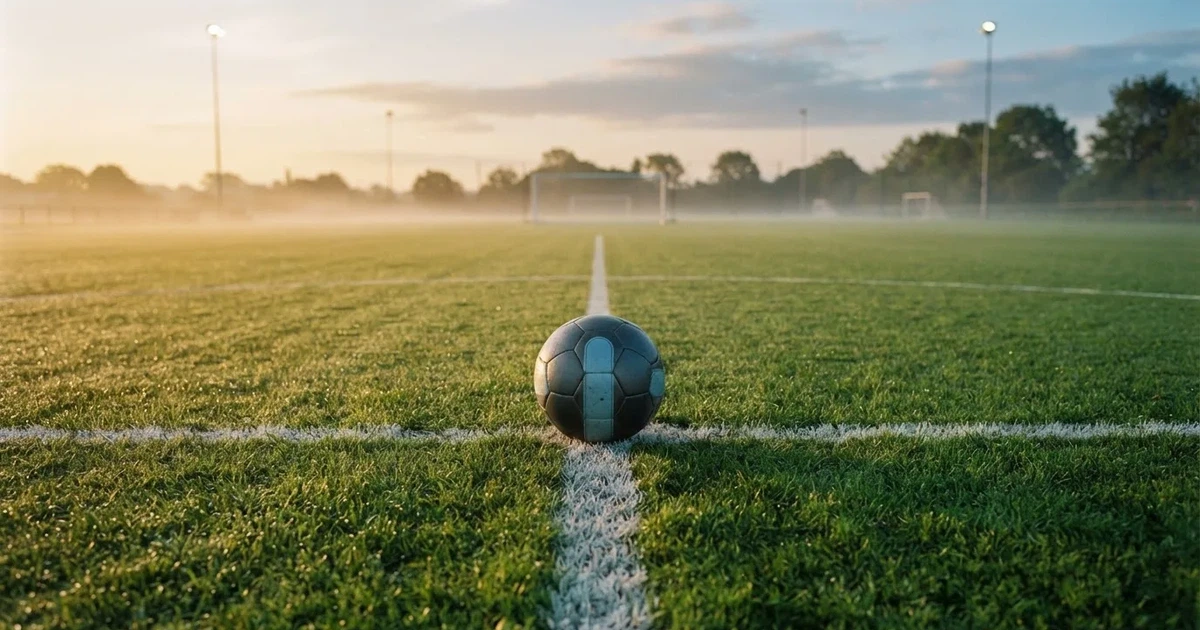 A ball on the centre spot of a grass pitch in morning light