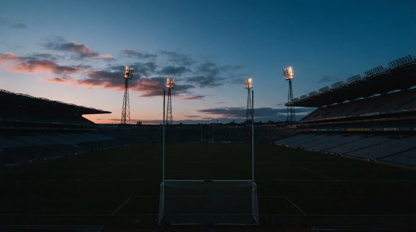An empty football stadium with floodlight masts at dusk