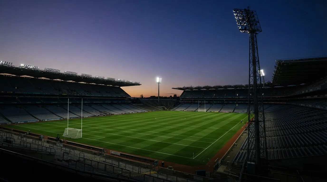 An empty football stadium with floodlight masts at dusk
