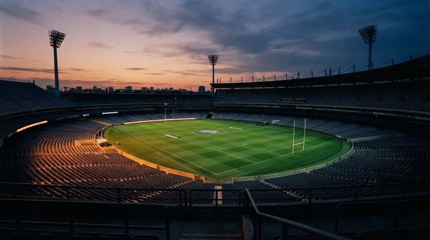An empty football stadium with floodlight masts at dusk