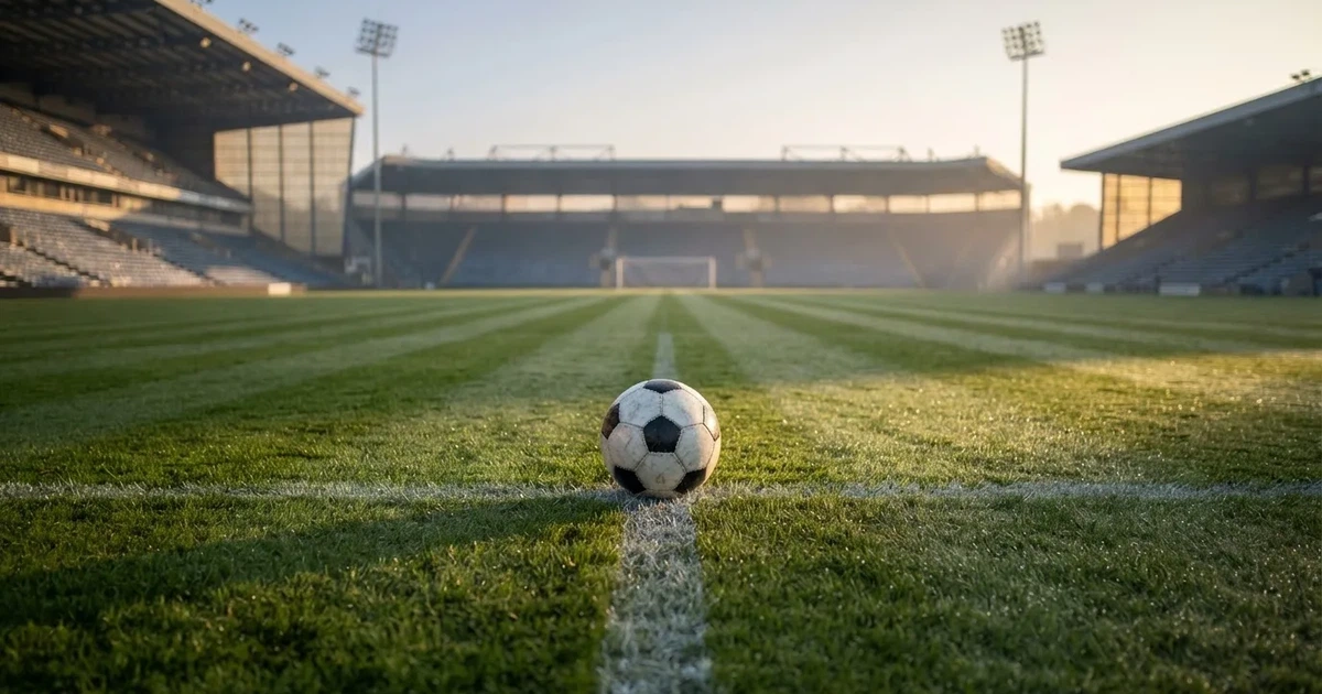A ball on the centre spot of a grass pitch in morning light